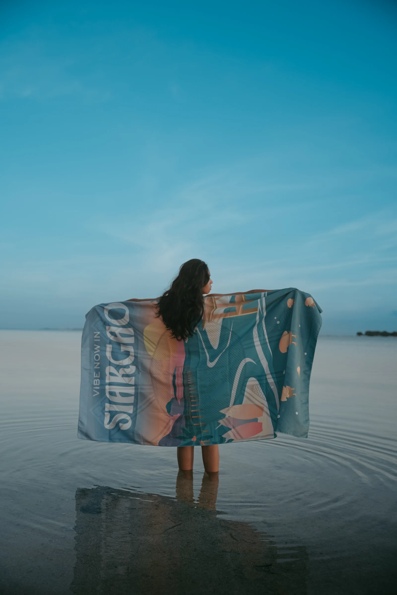 Model holding a Siargao towel open by the sea